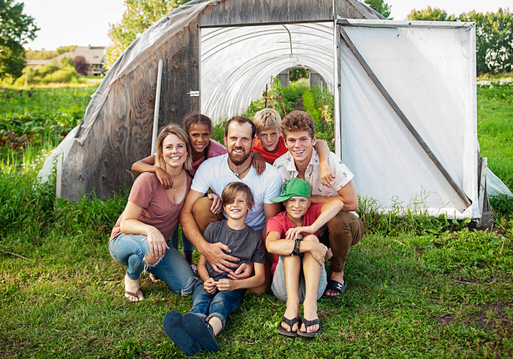 The Forstbauer family sits together in front of their garden at Grey Arrow Farm in Alberta, Canada.